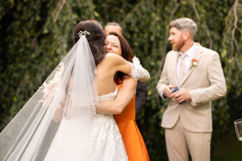 Wedding ceremony in the garden. Schloss Hünigen. Emotional and colorful wedding ceremony. Emotional hugs with family and friends after the wedding ceremony.