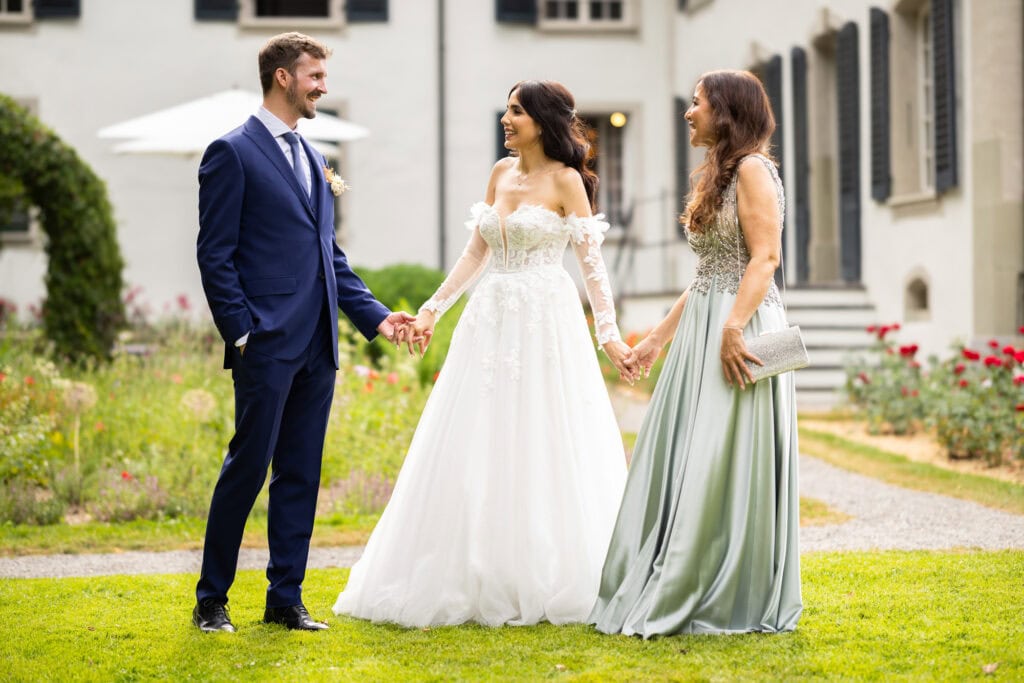 Wedding ceremony in the garden. Schloss Hünigen. Emotional and colorful wedding ceremony. Emotional hugs with family and friends after the wedding ceremony. Bride, groom and her mum