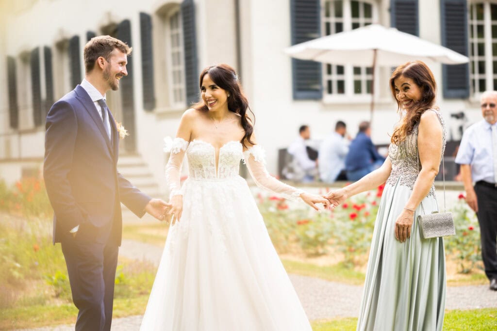 Wedding ceremony in the garden. Schloss Hünigen. Emotional and colorful wedding ceremony. Emotional hugs with family and friends after the wedding ceremony. Bride, groom and her mum