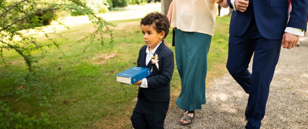 Wedding ceremony in the garden. Schloss Hünigen. Emotional and colorful wedding ceremony. Boy with bible