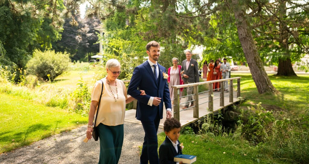 Wedding ceremony in the garden. Schloss Hünigen. Emotional and colorful wedding ceremony. Entry groom, family and friends