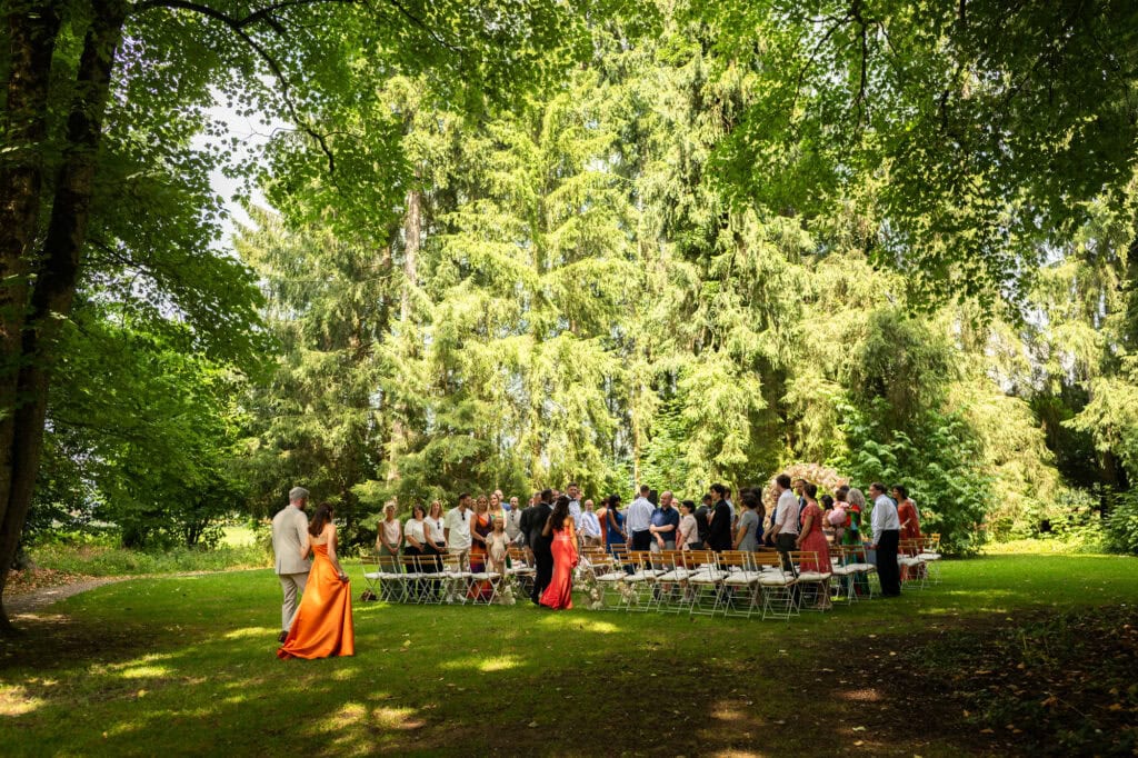 Wedding ceremony in the garden. Schloss Hünigen. Emotional and colorful wedding ceremony. Entry groom, family and friends