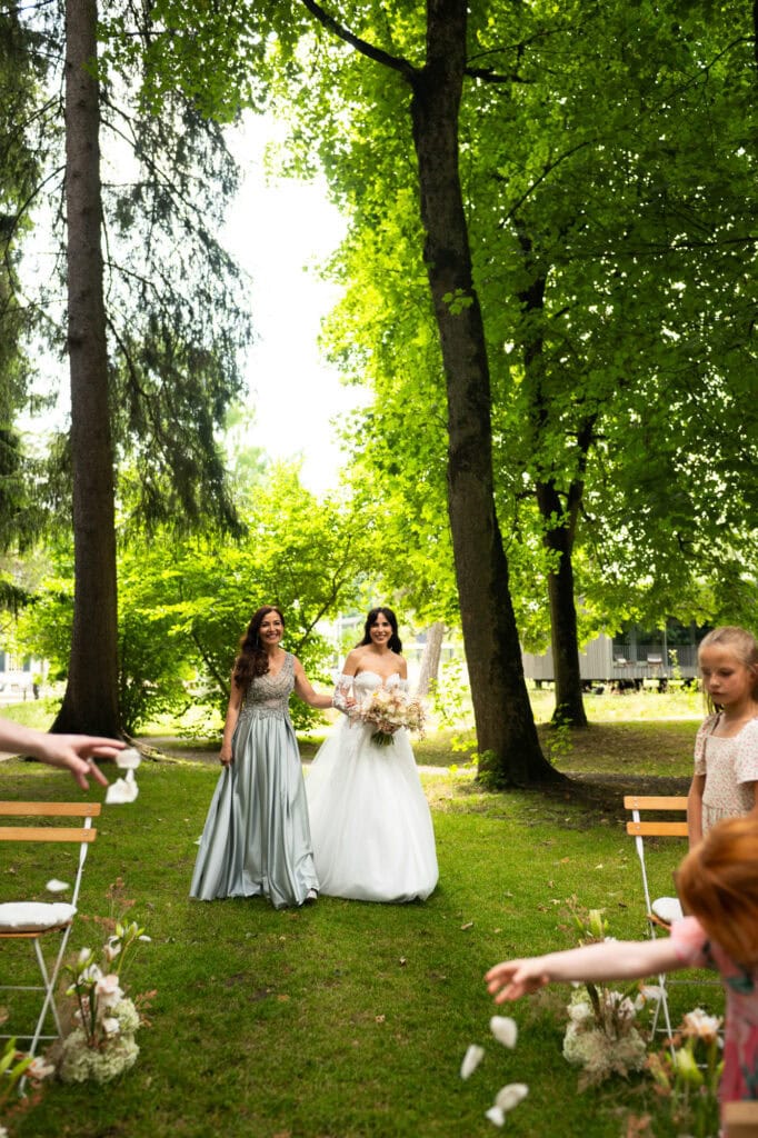 Wedding ceremony in the garden. Schloss Hünigen. Emotional and colorful wedding ceremony. Entry bride and her mum
