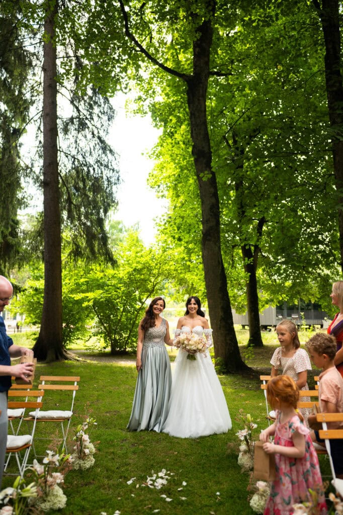 Wedding ceremony in the garden. Schloss Hünigen. Emotional and colorful wedding ceremony. Entry bride and her mum