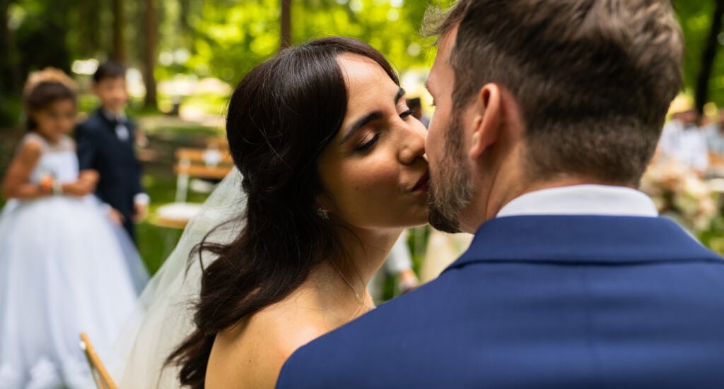 Wedding ceremony in the garden. Schloss Hünigen. Emotional and colorful wedding ceremony. Bride and groom kissing