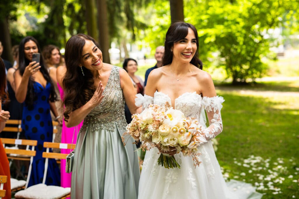 Wedding ceremony in the garden. Schloss Hünigen. Emotional and colorful wedding ceremony. Entry bride and her mum