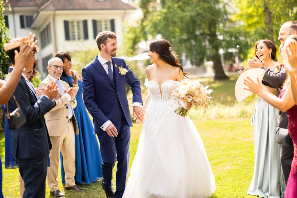 Guests forming a celebratory aisle (Spalier) for the bride and groom after the ceremony during their wedding at Schloss Hünigen in Bern