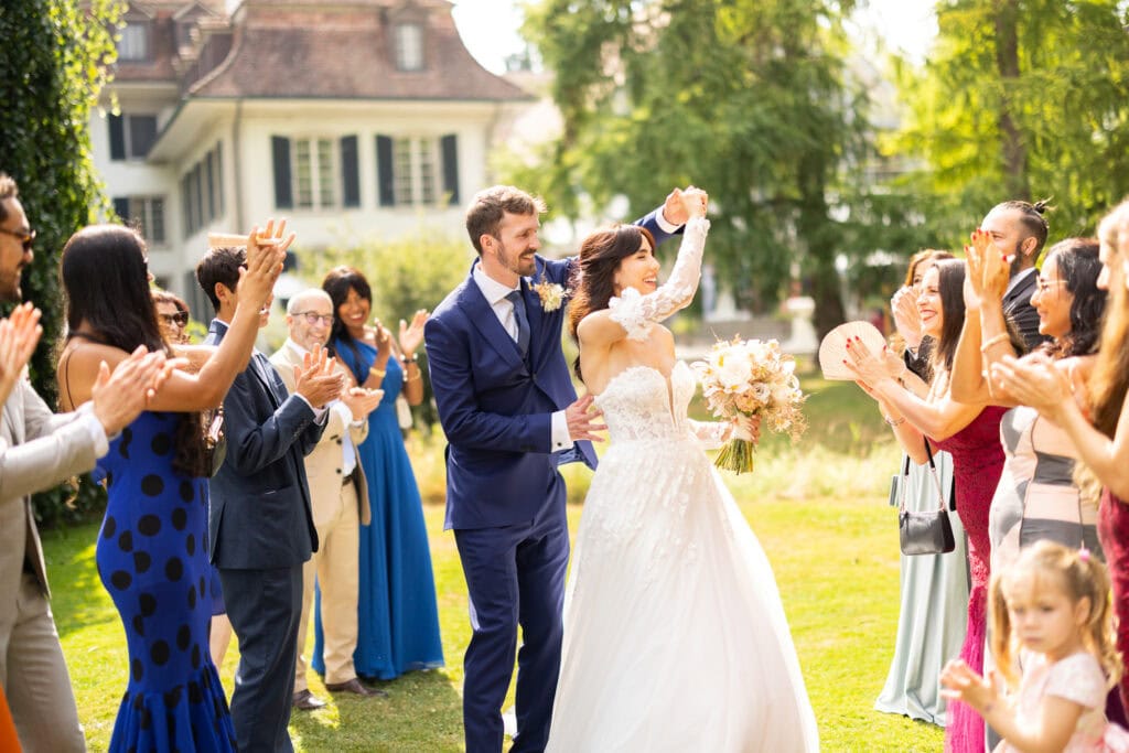 Guests forming a celebratory aisle (Spalier) for the bride and groom after the ceremony during their wedding at Schloss Hünigen in Bern