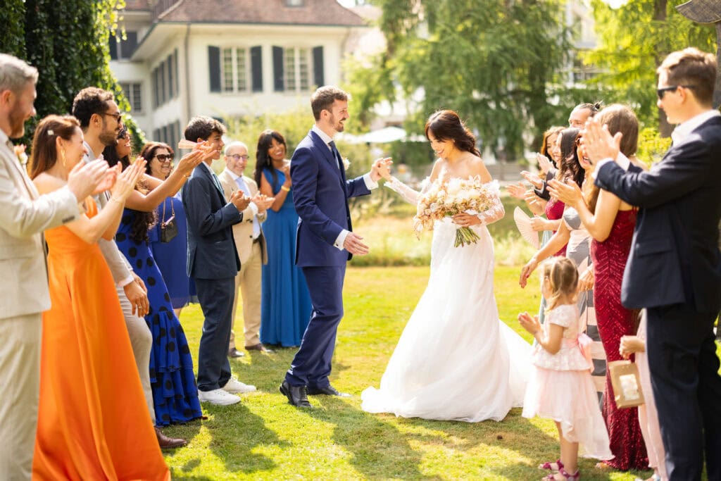 Guests forming a celebratory aisle (Spalier) for the bride and groom after the ceremony during their wedding at Schloss Hünigen in Bern
