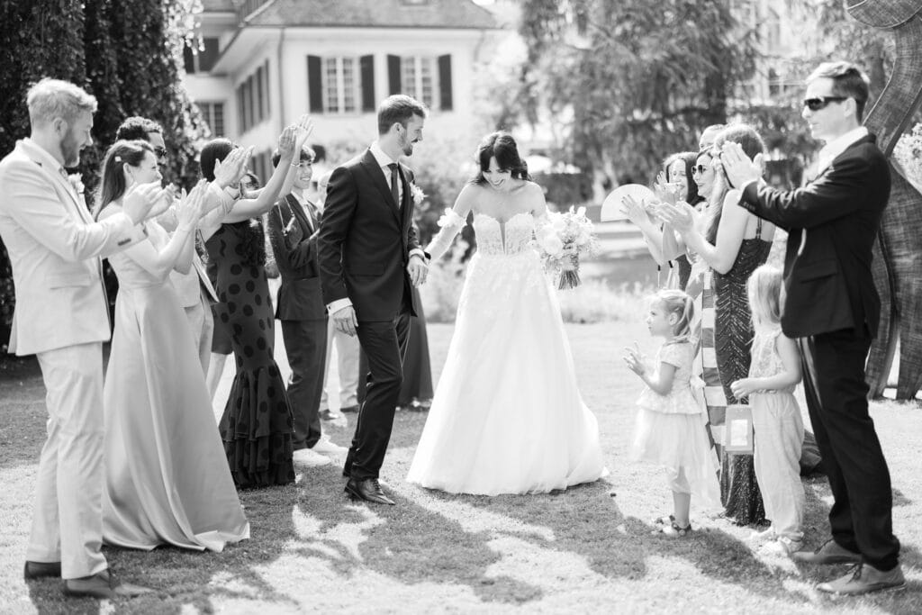 Guests forming a celebratory aisle (Spalier) for the bride and groom after the ceremony during their wedding at Schloss Hünigen in Bern