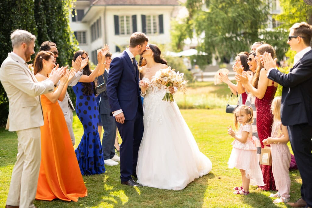 Guests forming a celebratory aisle (Spalier) for the bride and groom after the ceremony during their wedding at Schloss Hünigen in Bern