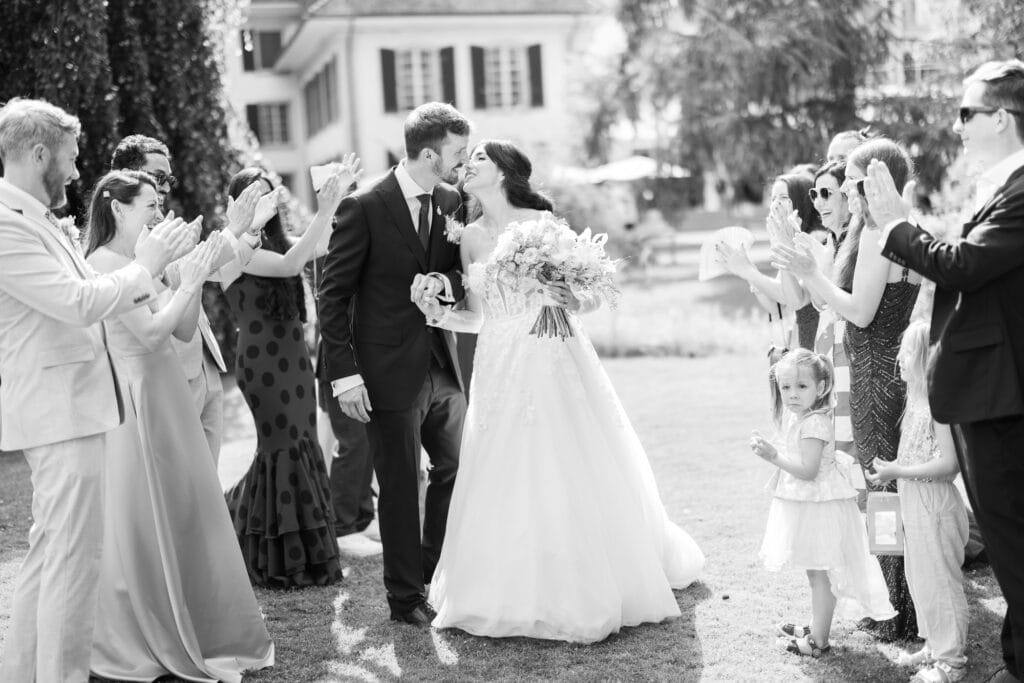 Guests forming a celebratory aisle (Spalier) for the bride and groom after the ceremony during their wedding at Schloss Hünigen in Bern