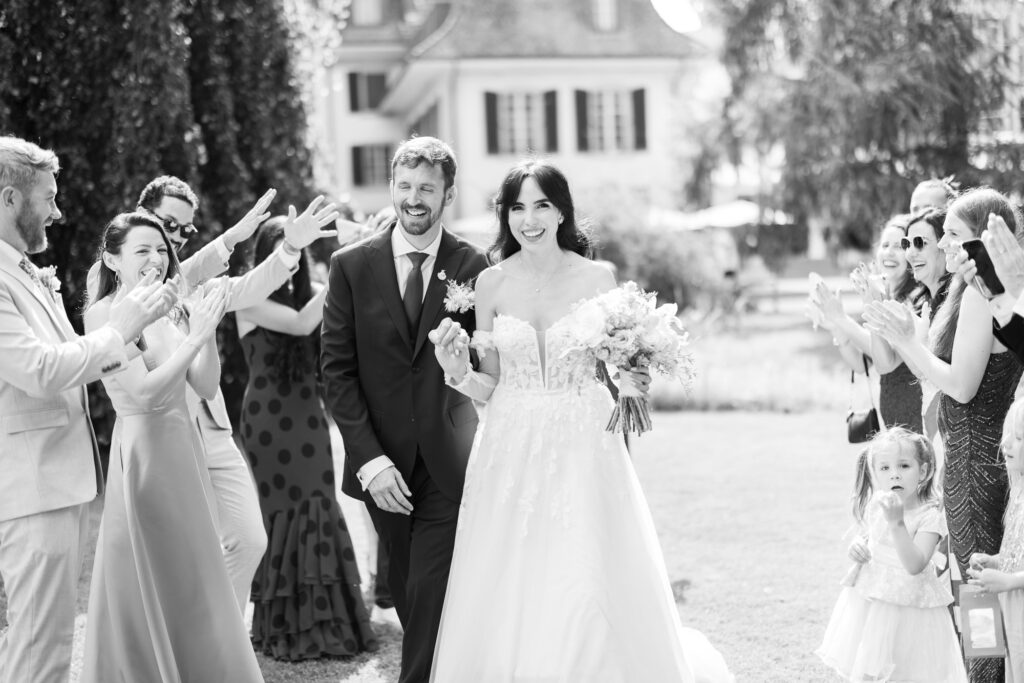 Guests forming a celebratory aisle (Spalier) for the bride and groom after the ceremony during their wedding at Schloss Hünigen in Bern